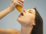 Adolescente desnuda bebiendo jugo de naranja